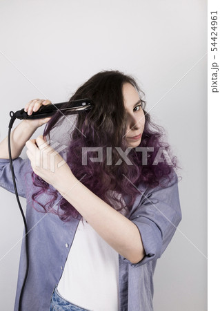 Young girl straightens curly hair of Flat Iron. Young girl straightens curly hair of Flat Iron. 54424961