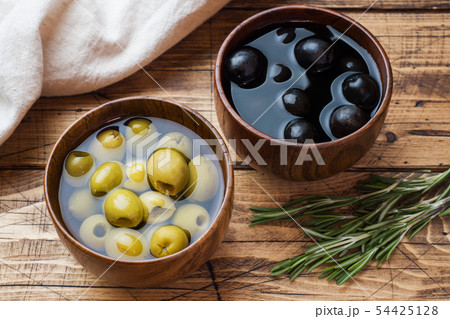 Black and green olives in wooden bowls on wooden Black and green olives in wooden bowls on wooden 54425128