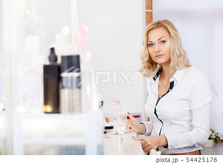 Make up artist doing professional makeup of young woman near the mirror in beauty studio 54425176
