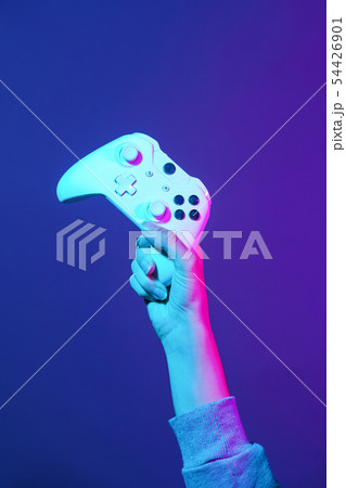 Hand with white gamepad on dark violet background. Hand with white gamepad on dark violet background. 54426901