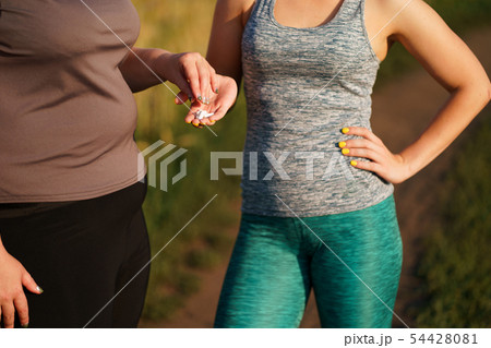 Overweight woman take slimming pills from friend 54428081
