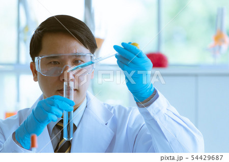 Scientist dropping blue liquid into test tube. 54429687