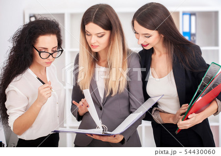 Team portrait of happy businesswomen standing on office corridor, looking at camera, smiling. Team portrait of happy businesswomen standing on office corridor, looking at camera, smiling. 54430060