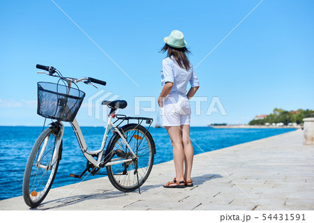 Young woman riding city bicycle near sea Young woman riding city bicycle near sea 54431591