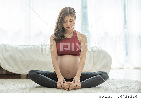 Asian Pregnant woman practice yoga in bedroom Asian Pregnant woman practice yoga in bedroom 54433324