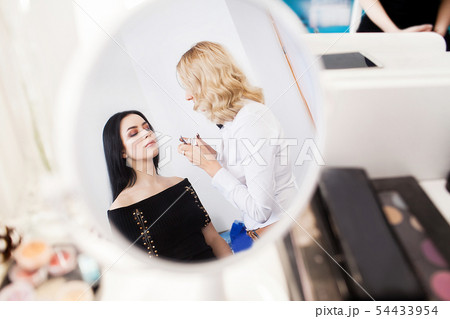 make up artist applying eye shadow to a woman make up artist applying eye shadow to a woman 54433954
