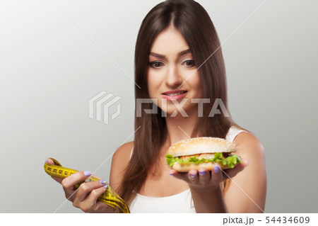Harmful food. A young girl is struggling with overweight and malicious food. The choice between Harmful food. A young girl is struggling with overweight and malicious food. The choice between 54434609