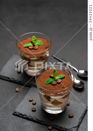 Classic tiramisu dessert in a glass on stone serving board on dark concrete background 54435021