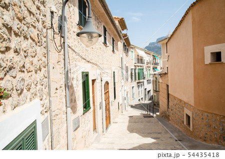 マヨルカ島の街並み　緑の遮光扉の付いた窓のある薄あずき色の壁と石壁の家々 54435418