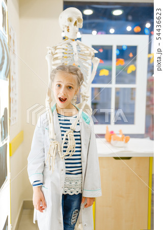 Girl in uniform near a skeleton, playing doctor Girl in uniform near a skeleton, playing doctor 54436623