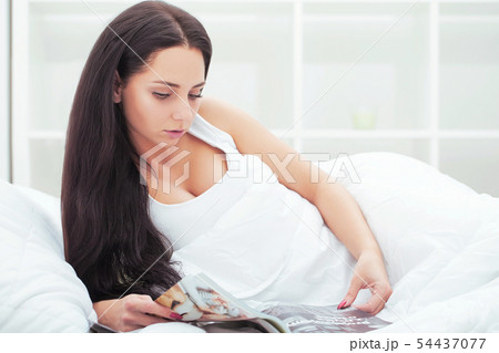 Woman awakens from long sleep in bed yawning and stretching in the morning on a sunny day Woman awakens from long sleep in bed yawning and stretching in the morning on a sunny day 54437077