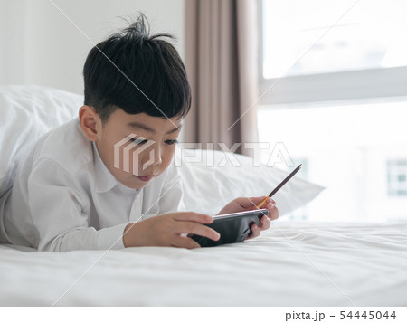 Cute little asian kid focused on smartphone Cute little asian kid focused on smartphone 54445044