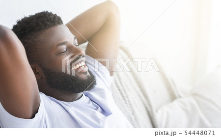 Satisfied black guy relaxing at home, lying with closed eyes Satisfied black guy relaxing at home, lying with closed eyes 54448071