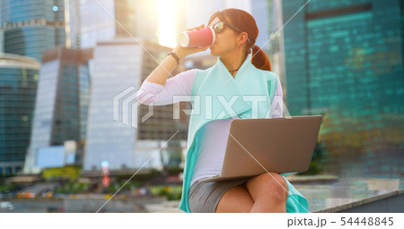 Portrait of business woman sitting with laptop and cup of coffee Portrait of business woman sitting with laptop and cup of coffee 54448845
