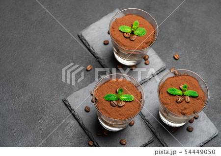 Classic tiramisu dessert in a glass on stone serving board on dark concrete background 54449050