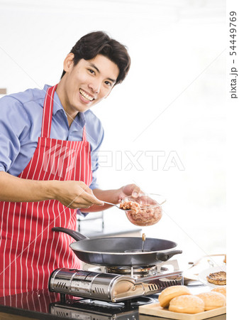Asian man put ground pork into pan on stove.. Asian man put ground pork into pan on stove.. 54449769
