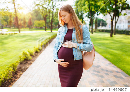 Happy pregnant girl is hugging her belly while 54449807