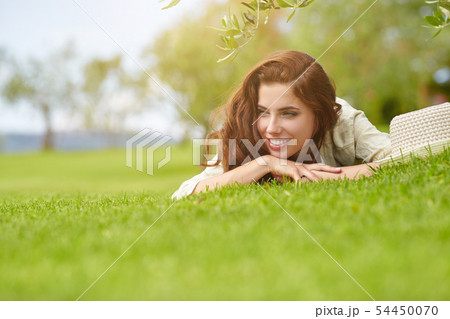 Beautiful smiling woman lying on a grass outdoor. Beautiful smiling woman lying on a grass outdoor. 54450070