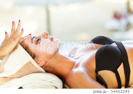 Spa mask. Cosmetologist smears cosmetic mask on the face of woman 54452245