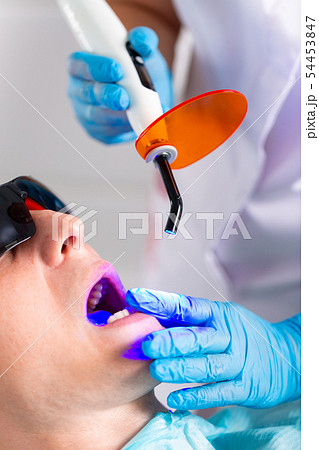Close-up portrait of a male patient at dentist in the clinic. Teeth whitening procedure with 54453847