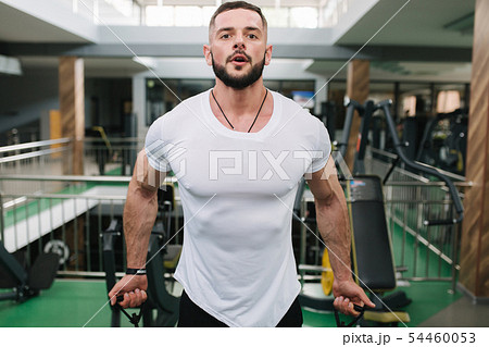 Man use elastic rof training in the gym. Man in white t-shirt trains inside Man use elastic rof training in the gym. Man in white t-shirt trains inside 54460053