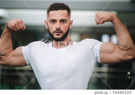 Young athlete posing with a torso for photography on a gym background. Bodybuilder, athlete with Young athlete posing with a torso for photography on a gym background. Bodybuilder, athlete with 54460104