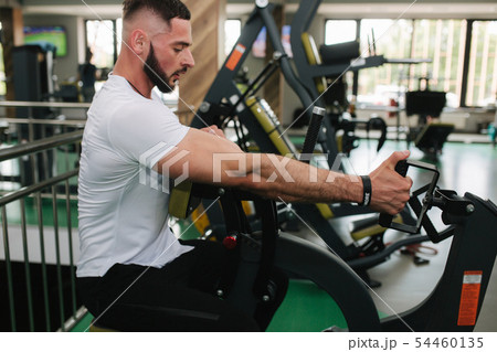 A young athlete trains in the gym. Bodybuilder trains the muscules of the back A young athlete trains in the gym. Bodybuilder trains the muscules of the back 54460135