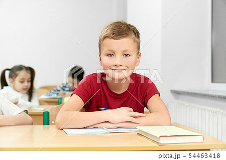 Male student sitting at desk with folded arms during lesson 54463418