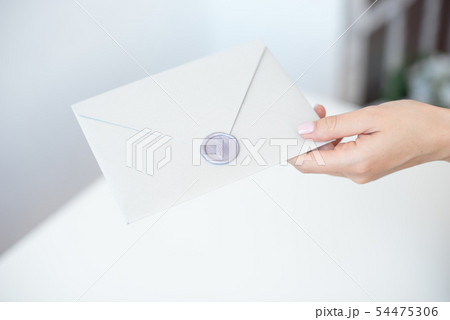 Close-up photo of female hands with wax seal with invitation envelope, gift certificate, postcard Close-up photo of female hands with wax seal with invitation envelope, gift certificate, postcard 54475306