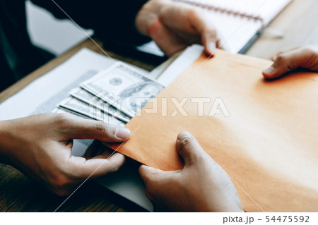 Businessman secretly giving a bribe by giving Businessman secretly giving a bribe by giving 54475592