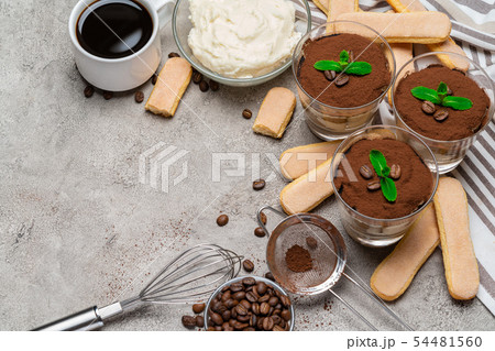 Frame made of Classic tiramisu dessert in a glass and savoiardi cookies on concrete background Frame made of Classic tiramisu dessert in a glass and savoiardi cookies on concrete background 54481560