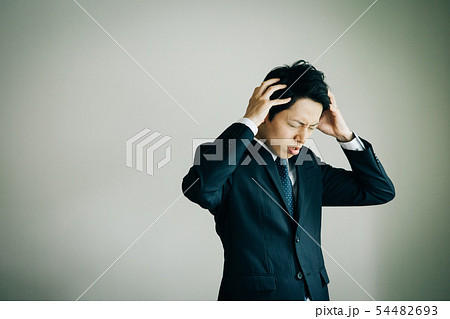 頭を抱えるビジネスマン 日本人男性 トラブル ショックの写真素材