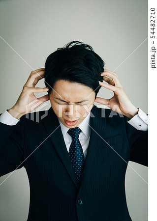 頭を抱えるビジネスマン 日本人男性 トラブル ショックの写真素材