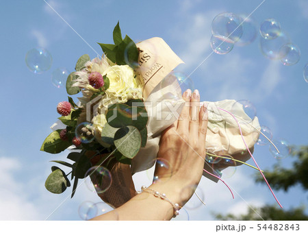 青空に映える真珠を付けた女性の手と花束 54482843