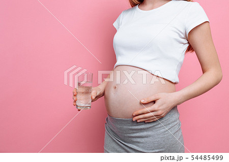 Pregnant girl holding a glass of water on the Pregnant girl holding a glass of water on the 54485499