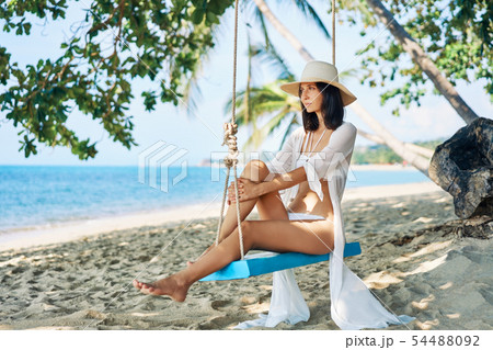 Happy woman relax on swing on beautiful paradises beach Happy woman relax on swing on beautiful paradises beach 54488092