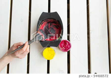 Color and hairdresser concept - female hairdresser in process of mixing hair dye color on the table Color and hairdresser concept - female hairdresser in process of mixing hair dye color on the table 54488572