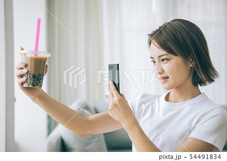 スマホでタピオカミルクティーを撮る若い女性 54491834