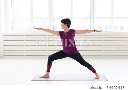 Healthy lifestyle, people and sport concept - Middle aged woman doing yoga 54492413