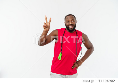 Shot of masculine man skipping rope. Muscular young man exercising with jumping rope against grey 54496902