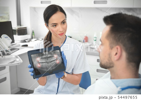 Female dentist showing teeth x-ray on tablet 54497655
