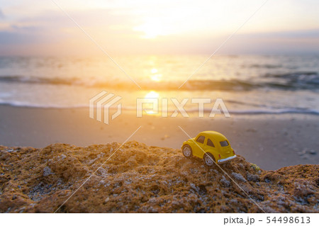 Yellow toy car on the beach in the sunlight in 54498613