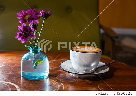 Cappuccino cup on table wih flowers in bottle Cappuccino cup on table wih flowers in bottle 54500526