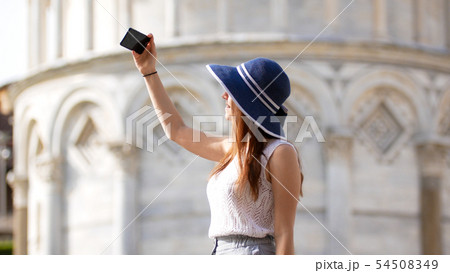 Young attractive woman stand under Pisa tower and take a selfie 54508349