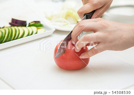 白背景でまな板でトマトを包丁で切っている背景にきゅうり 54508530