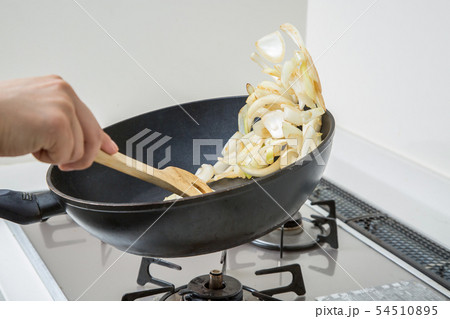 台所のキッチンでフライパンで玉ねぎを炒めている 54510895