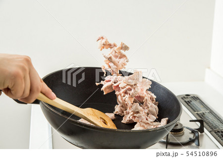 台所のキッチンでフライパンで豚肉を炒めている 54510896
