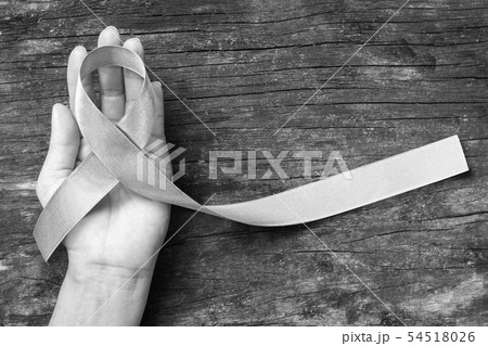 Silver color ribbon on hand support and aged wood Silver color ribbon on hand support and aged wood 54518026