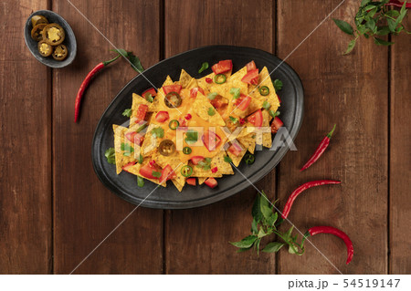 Nachos, Mexican tortilla chips, shot from the top with a cheese sauce, chili and jalapeno peppers Nachos, Mexican tortilla chips, shot from the top with a cheese sauce, chili and jalapeno peppers 54519147