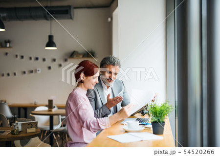 Man and woman having business meeting in a cafe, using laptop. 54520266